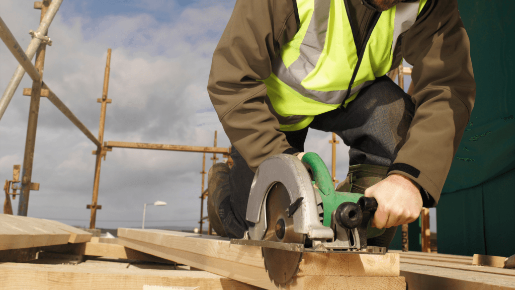 Tradesperson cutting timber with a power saw on a construction site