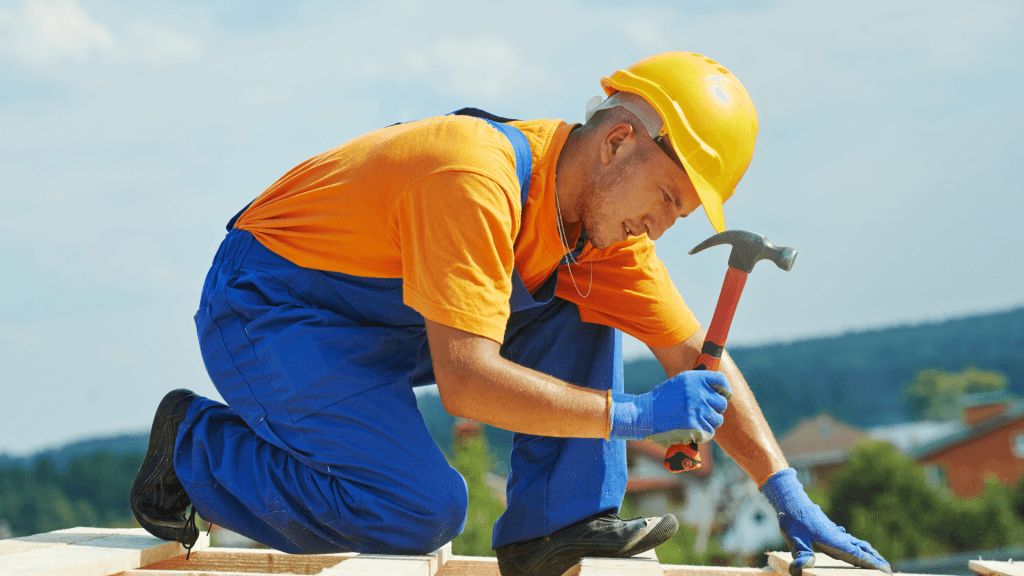 Carpenter in a hard hat hammering a timber frame outdoors