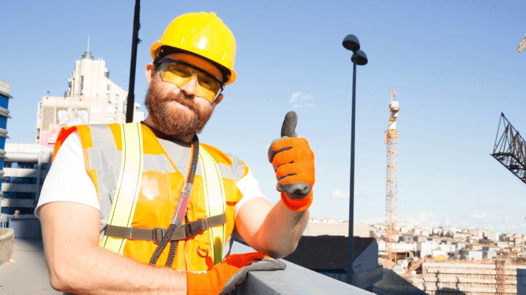 Construction worker in a hi-vis vest and hard hat giving a thumbs up on a building site